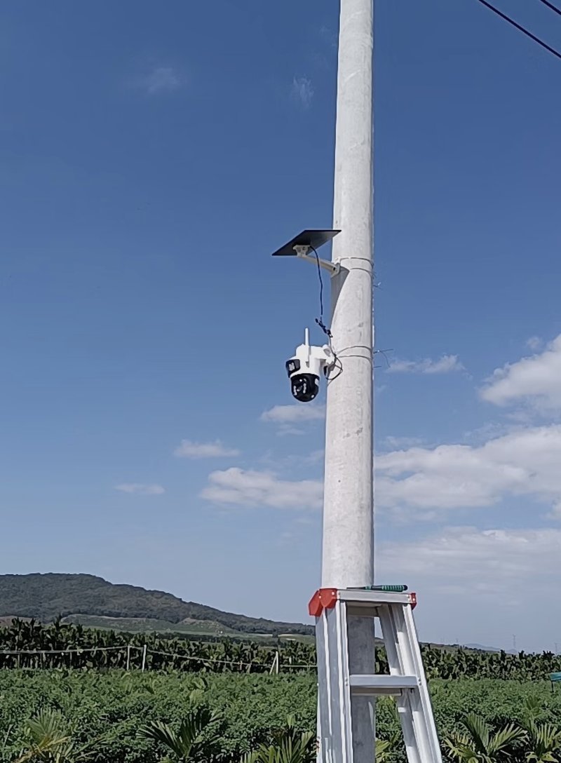 Installation of a solar camera light on a pole above farm plots